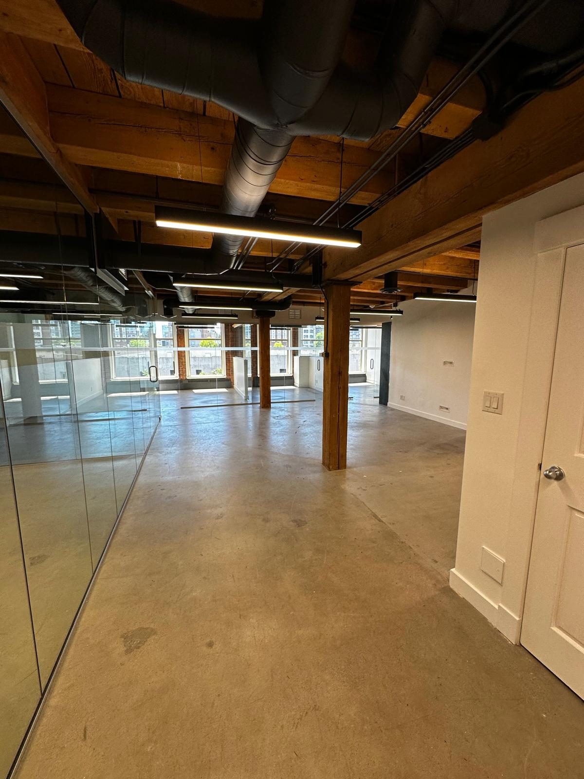 Open office at The Landing with the original heavy-timber structure, new lighting and glass partitions